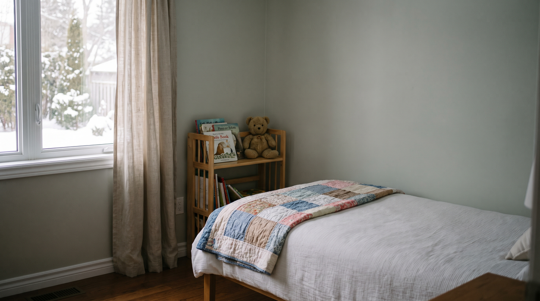 A softly lit child's bedroom with a neatly made bed, picture books on a low shelf and a soft toy.