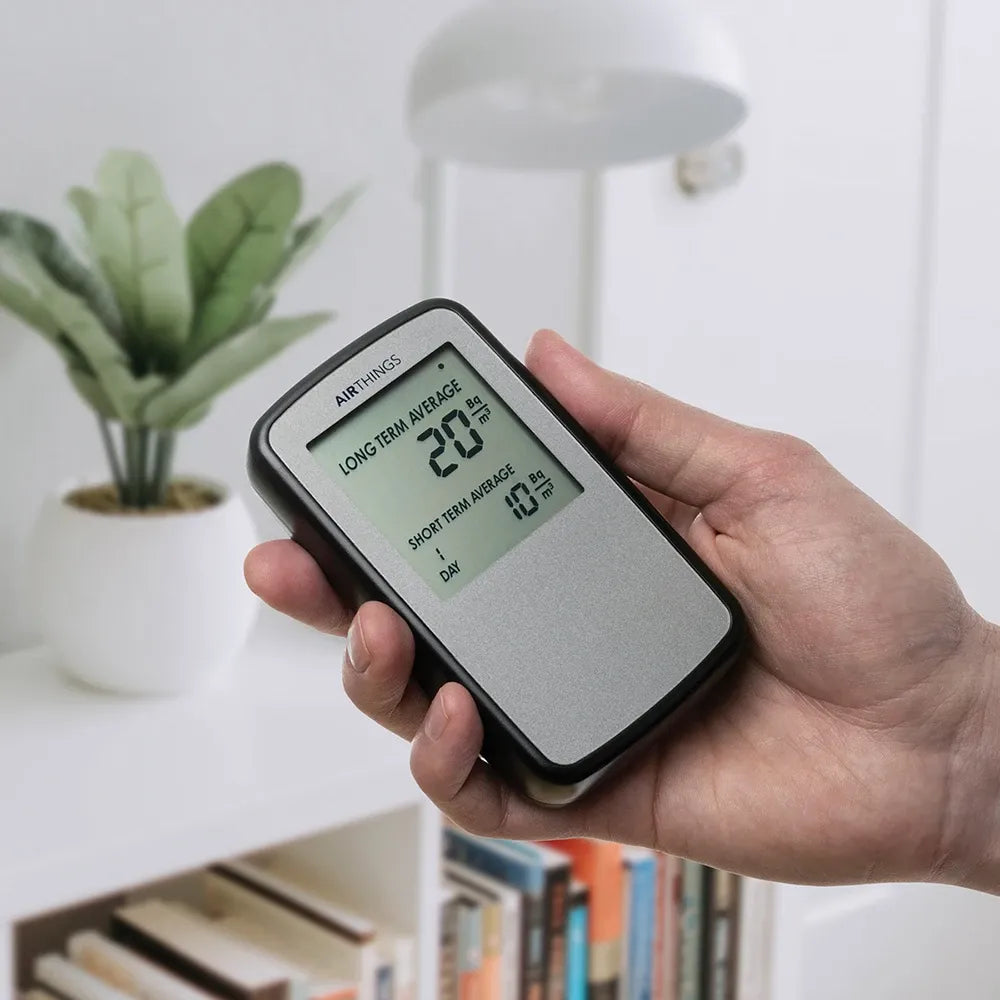 Corentium Home radon monitor held in hand — palm-sized, readings on screen